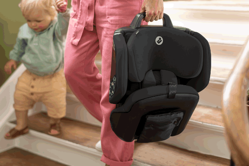 Maxi Cosi Nomad Plus folded and carried by parent with toddler on stairs